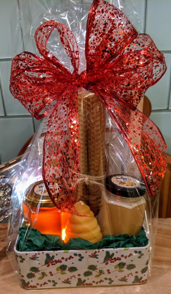 A Honey Hive's Holiday Christmas Basket, featuring a Holiday Tin, and Honey, Creamed Honey, and Beeswax candles.