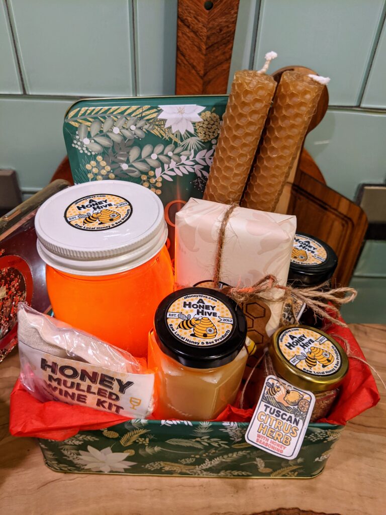 A Honey Hive Bee honey, bee honey inspired seasonings, Creamed honey, Honey Mulled wine kit, Honey soaps, Beeswax candles, and in a Holiday gift Christmas tin basket set.
